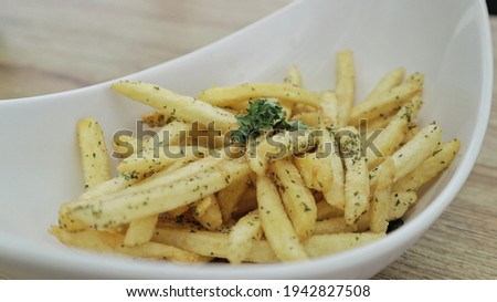 French fries topped with oregano and parsley garnish Royalty-Free Stock Photo #1942827508