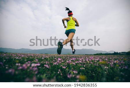 Female runner running in wild spring field Royalty-Free Stock Photo #1942836355