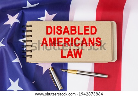 Law and order concept. Against the background of the flag of the United States of America lies a notebook with the inscription - DISABLED AMERICANS LAW