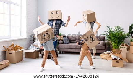 Carefree parents and kids in carton boxes on heads dancing in new spacious flat while having fun and enjoying relocation together Royalty-Free Stock Photo #1942888126