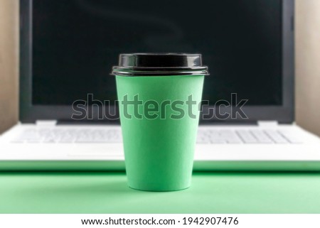 Workspace table with white laptop computer and Disposable Eco Paper Cup with coffee. Copy space for text, minimalism