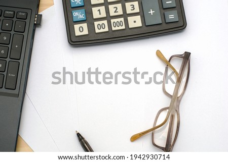 laptop calculator glasses and fountain pen on sheets of white copy space paper. High quality photo