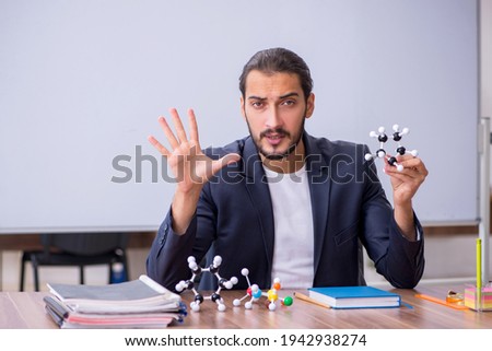 Young male teacher physicist in the classroom Royalty-Free Stock Photo #1942938274
