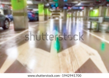 Parking lot cars blurred. Car lot parking space in underground city garage. Empty road asphalt background in soft focus. Industrial Shed or Parking Lot