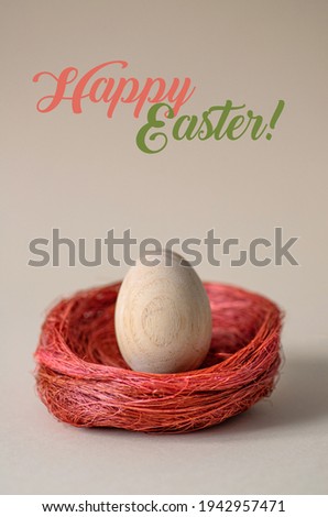 One Easter egg in a decorative nest on a neutral pastel background. Minimalistic trendy close up composition. Greeting card with text Happy Easter 