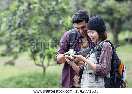 
A backpacker couple went hiking and were looking at the pictures they took. The two of them were very happy.