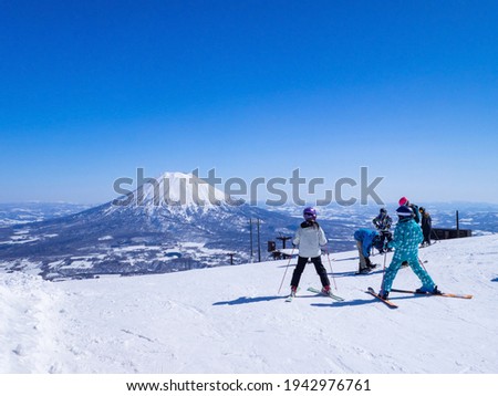 Skiers looking at snowy volcano on a clear day in early spring (Niseko, Hokkaido, Japan)