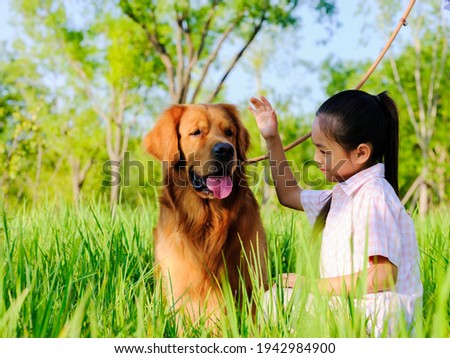 A happy girl and pet dog are playing in the park