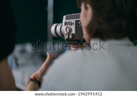 Female director of photography with a film camera on the shooting. Modern filming process of a film, advertising on the set.