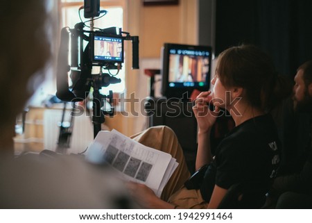 Director at work on the set. The director works with a group or with a playback while filming a movie, advertising, or a TV series. Shooting shift, equipment and group. Modern photography technique. Royalty-Free Stock Photo #1942991464