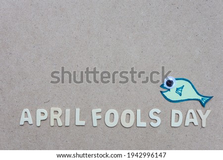 April Fools' Day text made with wood with a paper fish. Happy April Fools Day. 