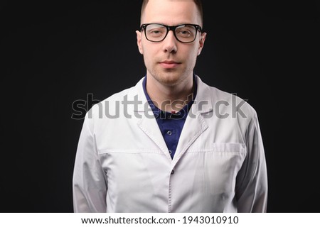 Portrait of unhappy tired young doctor with stethoscope with headache on dark background. Problems with the medic