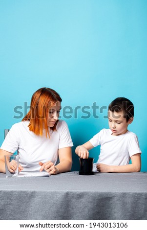 Children's creativity. mom and child son paint watercolor homework for kindergarten on blue background