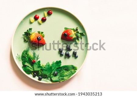 red strawberry in shape of fishes with green vegetable plant, sea world isolated