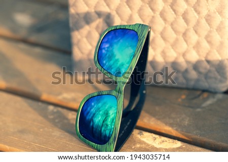Classic sunglasses model with blue reflecting lenses and green frame in a sunny day outside closeup . Selective focus