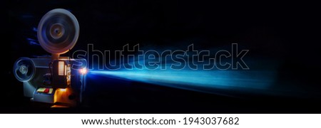working movie projector for viewing amateur films against a dark background indoors. Web banner. Blurred background. Royalty-Free Stock Photo #1943037682