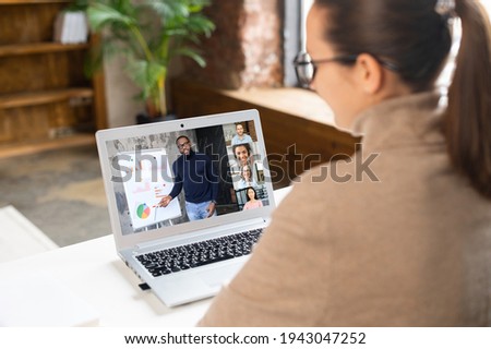 African male teacher, online tutor or business coach is conducting webinars, training, video classes on the laptop screen, a young woman is watching, other people involved. E-learning, online meeting Royalty-Free Stock Photo #1943047252
