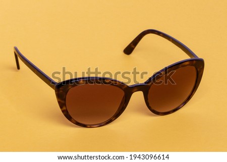 Summer glasses fashion concept. Closeup of trendy brown sun glasses on a yellow background. Copy space. Macro.