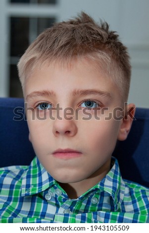 Young boy watch television in living room. Kid with blue eyes while watching TV. Close up view