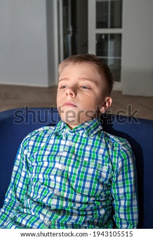 Young boy watch television in living room. Kid with blue eyes while watching TV
