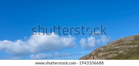 Panoramic photograph of a mountain top with low cloud and a clear blue sky, ready to overlay text or copy. 