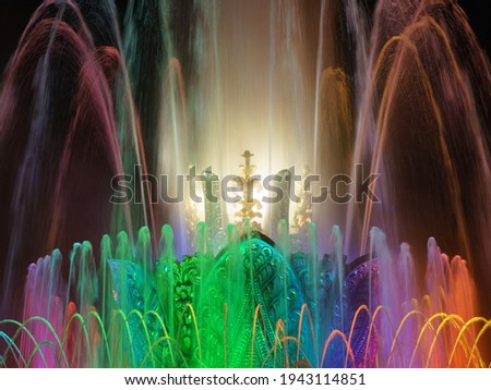 Long exposure photography of colorful fountain sprays in blue, green, pink neon illumination. Water rainbow. Bright night in the Moscow public park. High resolution image.