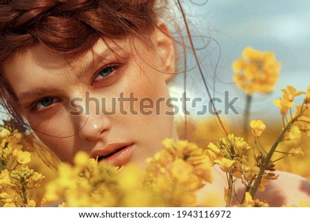  Young fashion model portrait with ginger hair and blue eyes in yellow rapeseed field Royalty-Free Stock Photo #1943116972