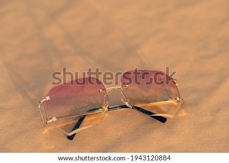 Futuristic sunglasses rimless design with pink lenses and golden frame shoot outside in a sunny day. Selective Focus 
