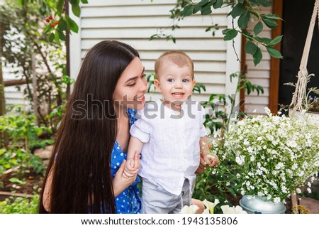 Content woman with cute little child relaxing in wooden gazebo in garden while spending weekend in countryside