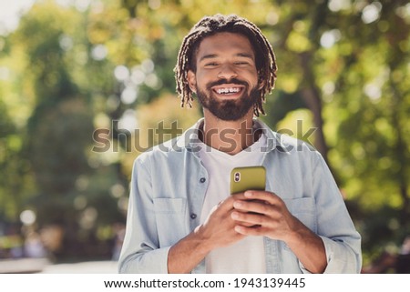 Photo of brunette handsome dark skin happy young man hold smartphone weekend city park in outside outdoors