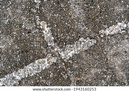 Old shabby weathered lane markings on the asphalt pavement of an abandoned street playground. Ruins of a basketball court. Abstract background