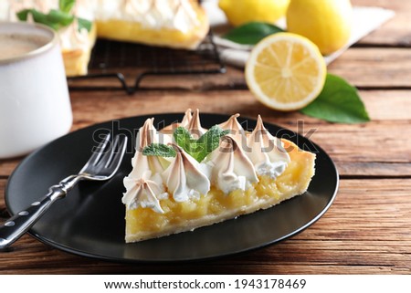Piece of delicious lemon meringue pie served on wooden table