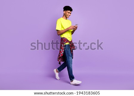 Full length body size photo of hipster using smartphone browsing internet smiling isolated on pastel purple color background