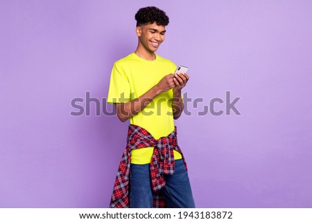 Photo portrait of young curly guy keeping smartphone reading news smiling isolated on pastel violet color background