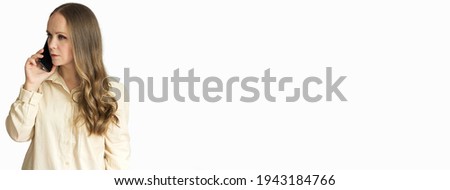 A girl in a beige shirt stands on a white background and talks on the phone. She has a European appearance, long blonde hair. horizontal. Banner. There's a lot of room for text. copy space.