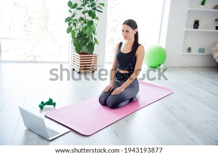Full size portrait of pretty girl sit on pink fitness carpet look interesting laptop morning workout home indoors