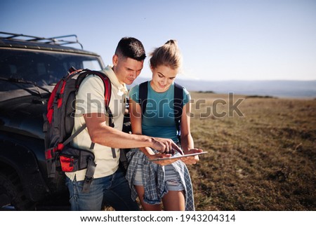 Couple hiking people using internet and tablet computer pc guide book Royalty-Free Stock Photo #1943204314