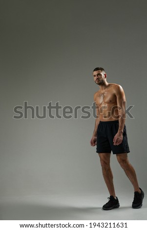Strong bearded sportsman posing at the photo camera isolated on grey background of a studio
