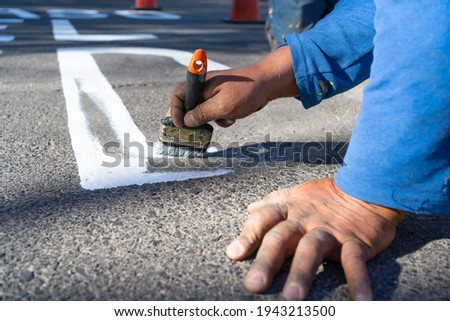 The worker is making a letter from the road sign on the avenue.