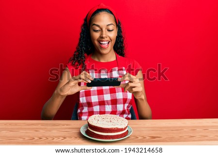 Young african american girl wearing baker apron making carrot cake picture celebrating crazy and amazed for success with open eyes screaming excited. 