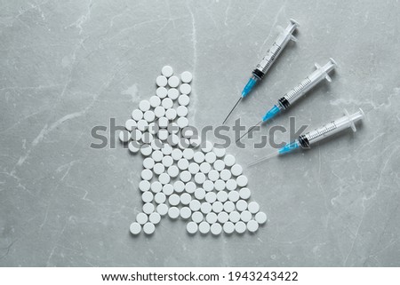 Rabbit figure of pills and syringes on light marble table, flat lay. Stop animal tests