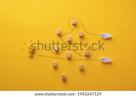 Two paper origami made boats trying to reach their goals and ambitions by travelling different paths. Royalty-Free Stock Photo #1943247529