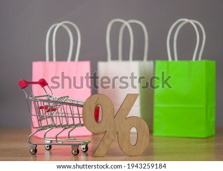 E-commerce online shopping idea concept. Trolley cart with colorful paper shopping bag on wooden table. Copy space.
