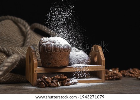 Cupcakes sprinkled with powdered sugar on a dark background. Confectionery on a black background. Walnut muffins