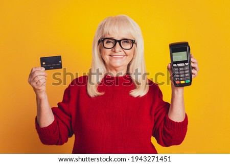 Photo of charming aged lady holding credit card wireless terminal paypass