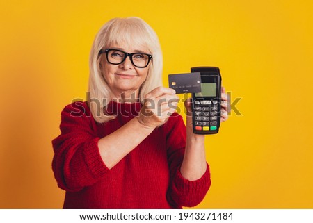 Photo of charming aged lady holding credit card wireless terminal payment concept