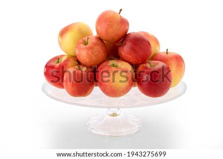 fuji apples on clear glass raised plate, red and yellow fruits isolated on white background