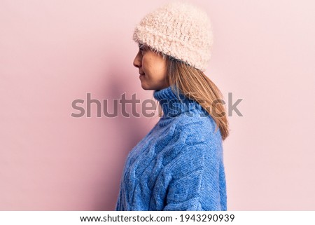 Young beautiful woman wearing winter clothes looking to side, relax profile pose with natural face with confident smile. 