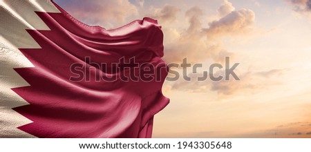 Qatar flag in the blue sky. Horizontal panoramic banner.