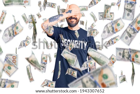 Young handsome man wearing security t shirt smiling and laughing with hand on face covering eyes for surprise. blind concept.